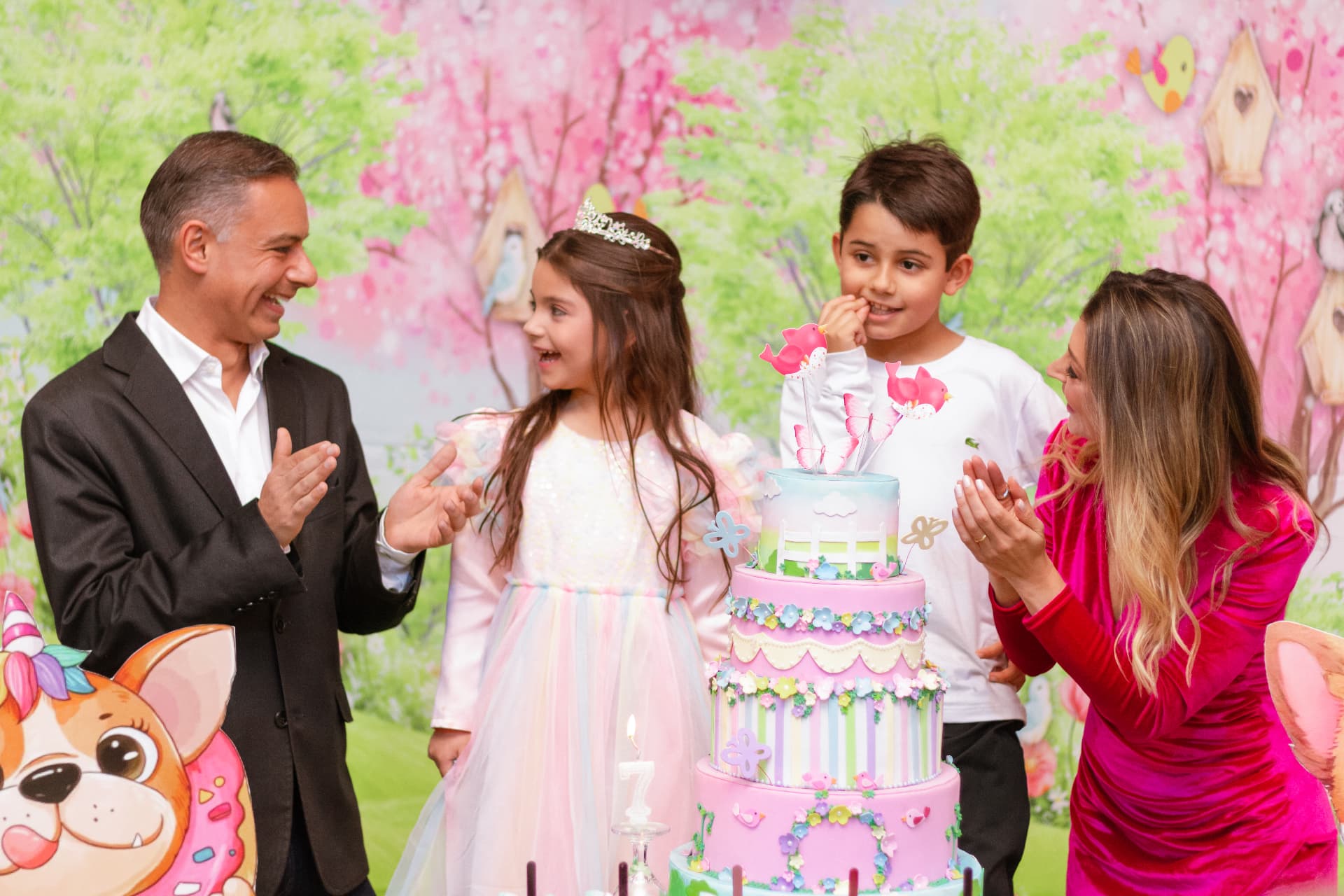 Família cantando parabéns em volta do bolo em festa infantil